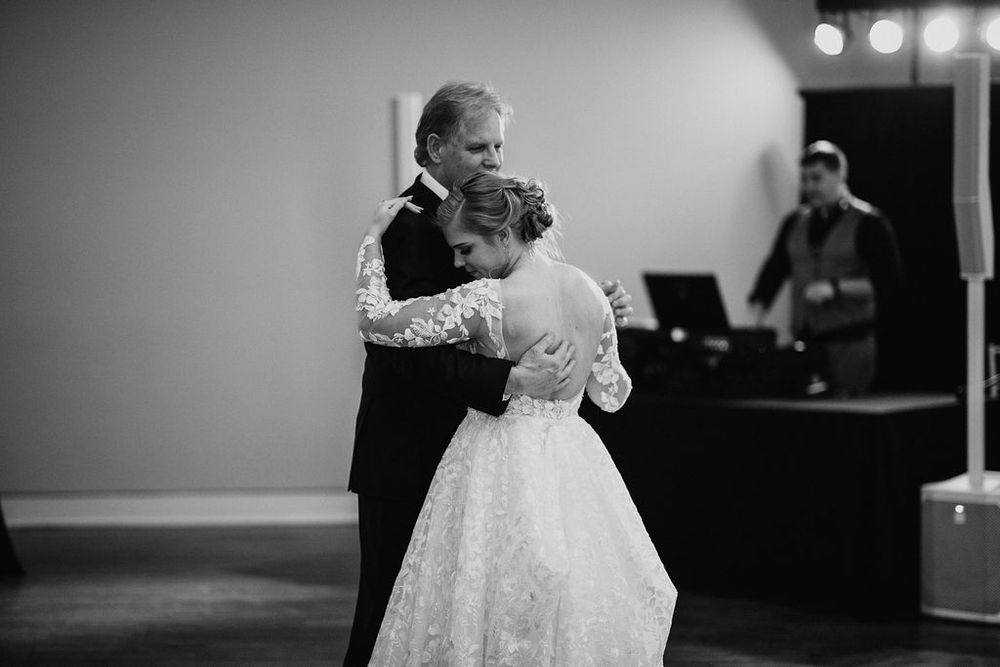 Black and white photo of bride and father sharing emotional father-daughter dance.