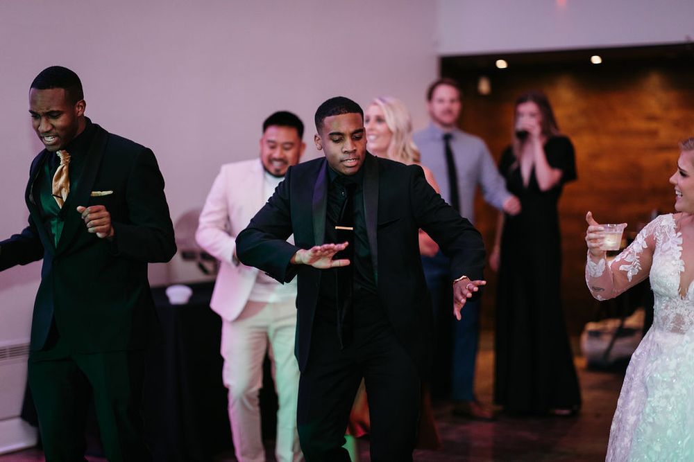 Guests in formal attire dancing energetically on the dance floor at a wedding reception.