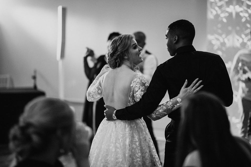 Bride and groom share their first dance in black and white wedding photo with lace dress.