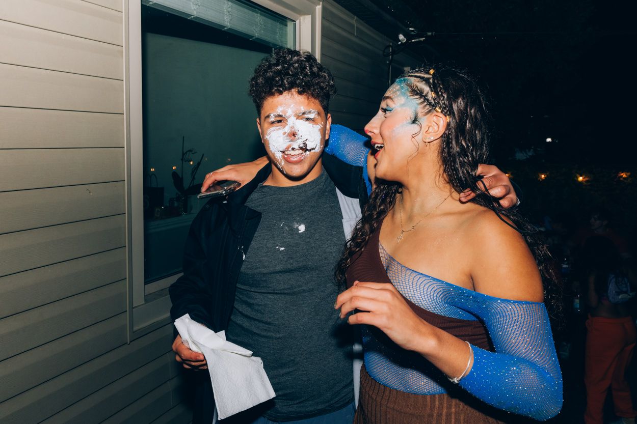 Two partygoers in festive attire posing together outside at night.