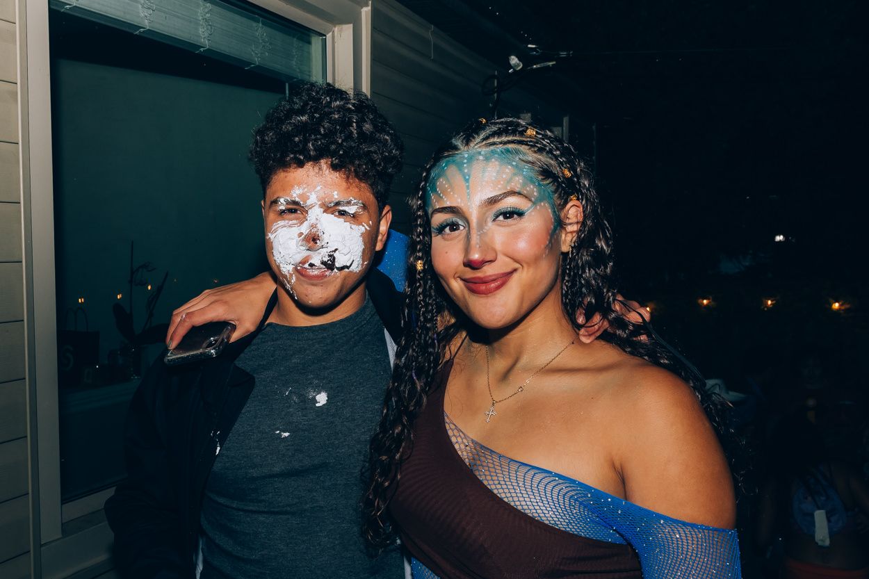 Two partygoers with festive makeup and attire posing together at night.