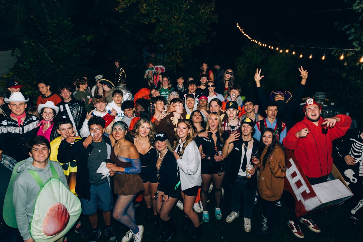 Large group photo of costumed partygoers celebrating outdoors at night.