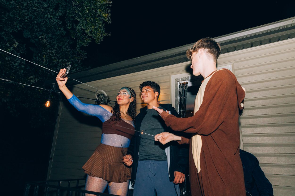 Group of friends taking selfies at an outdoor party.