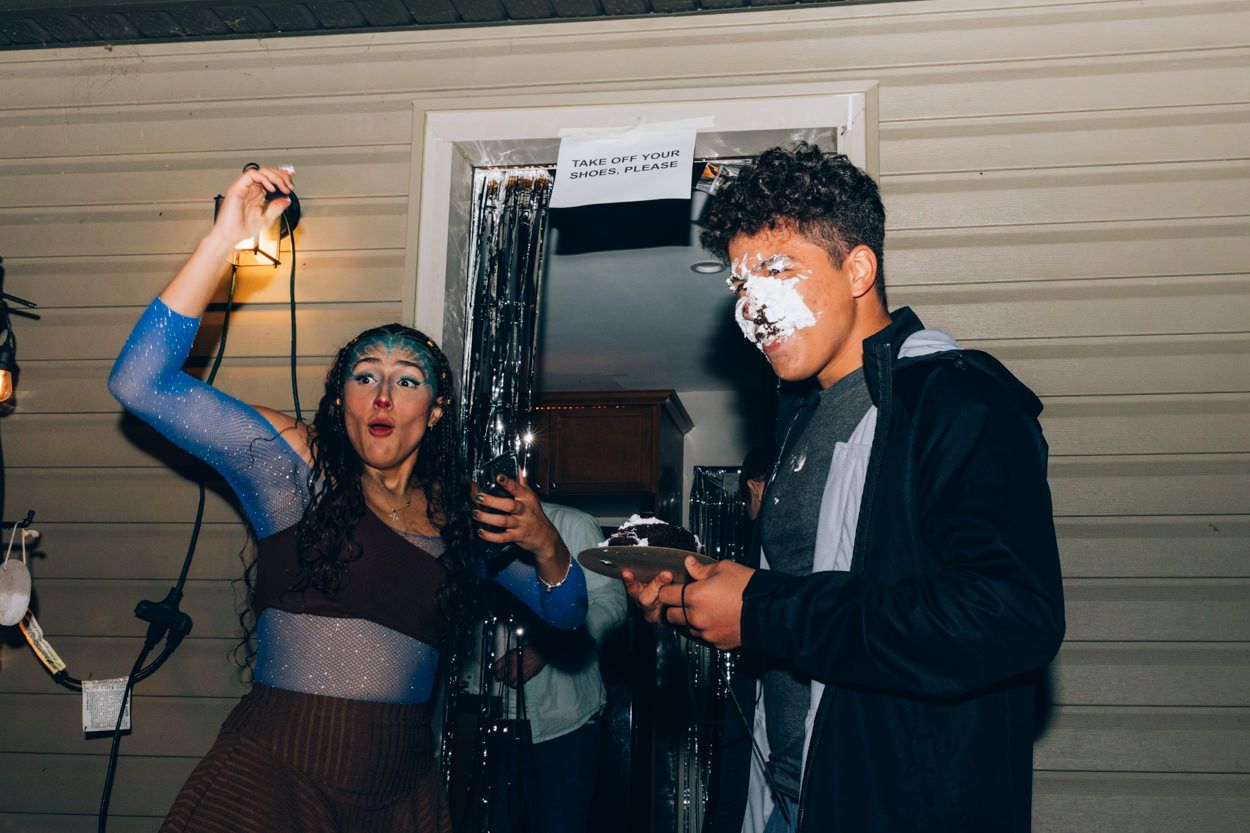 Two partygoers sharing drinks and having an animated moment at a nighttime gathering.
