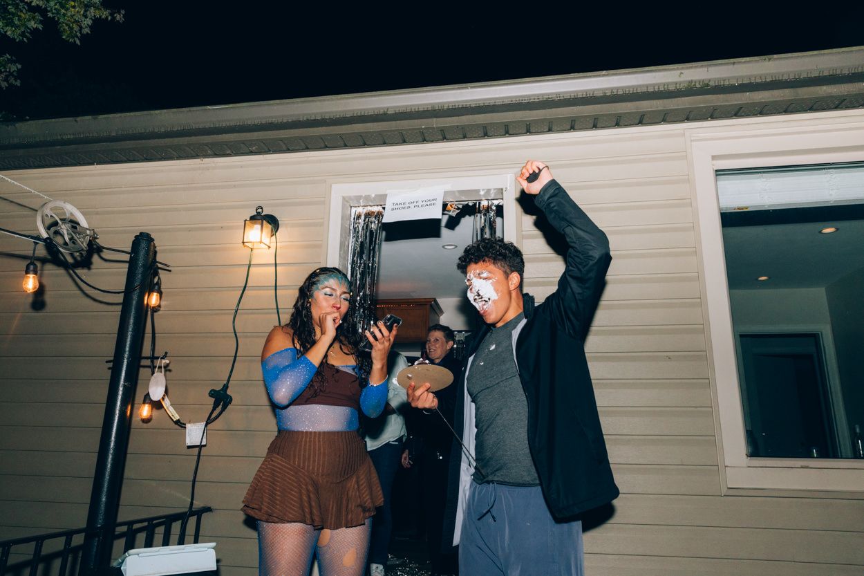 Group celebrating and posing together outside a house at night.