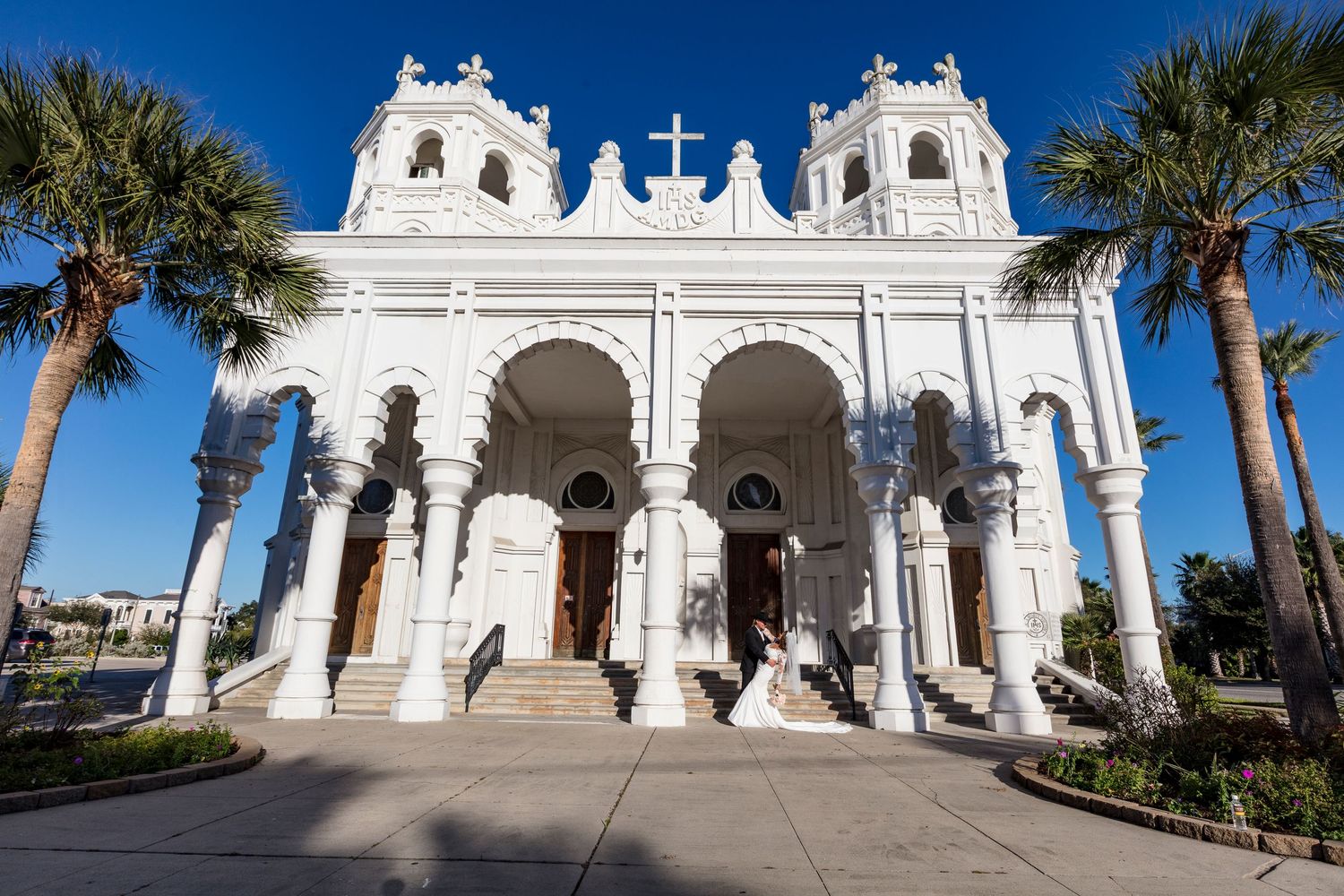 Elegant white Spanish colonial style church exterior with palm trees against blue sky in Florida.
