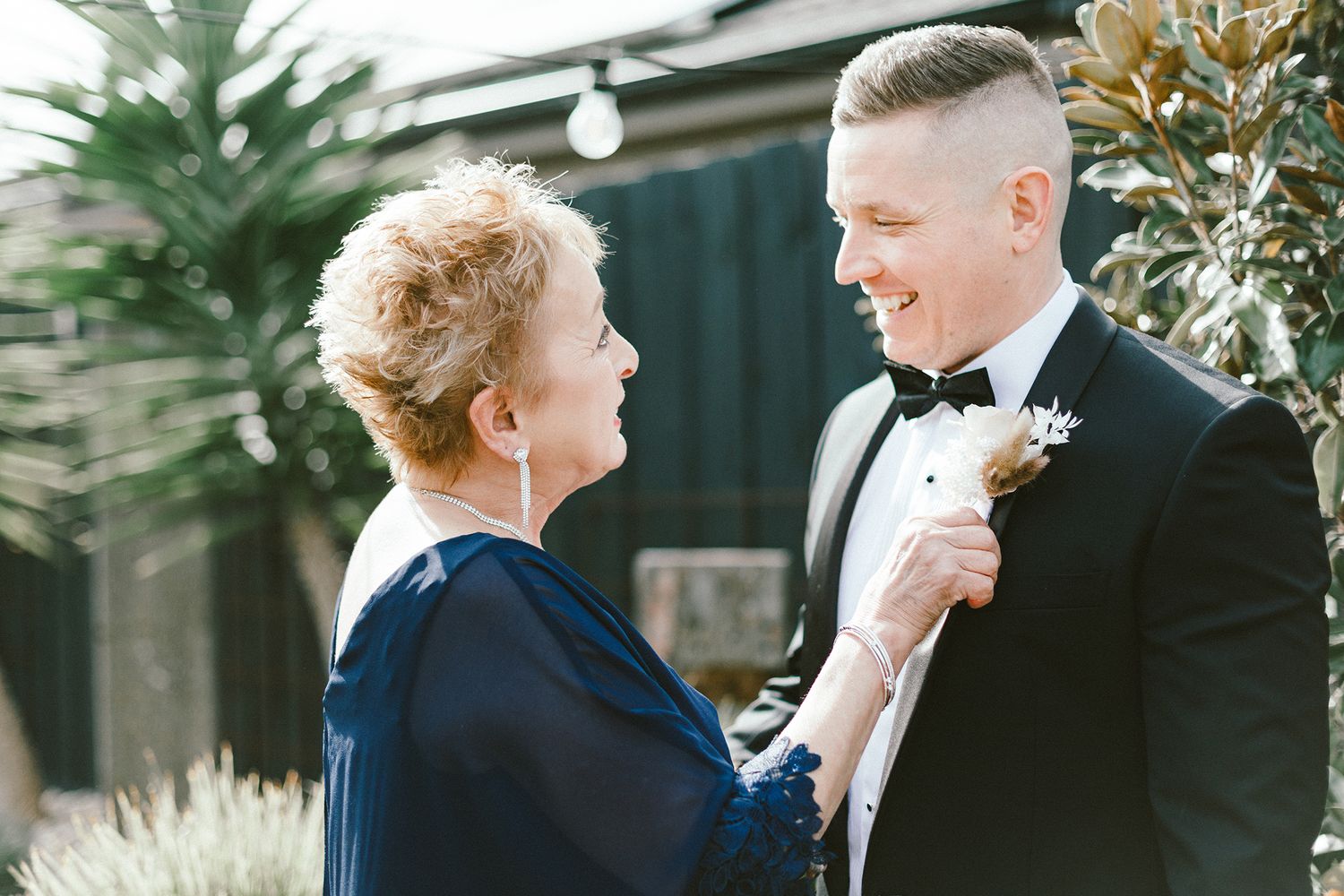 A heartwarming moment between two people in formal wear standing in a garden setting.
