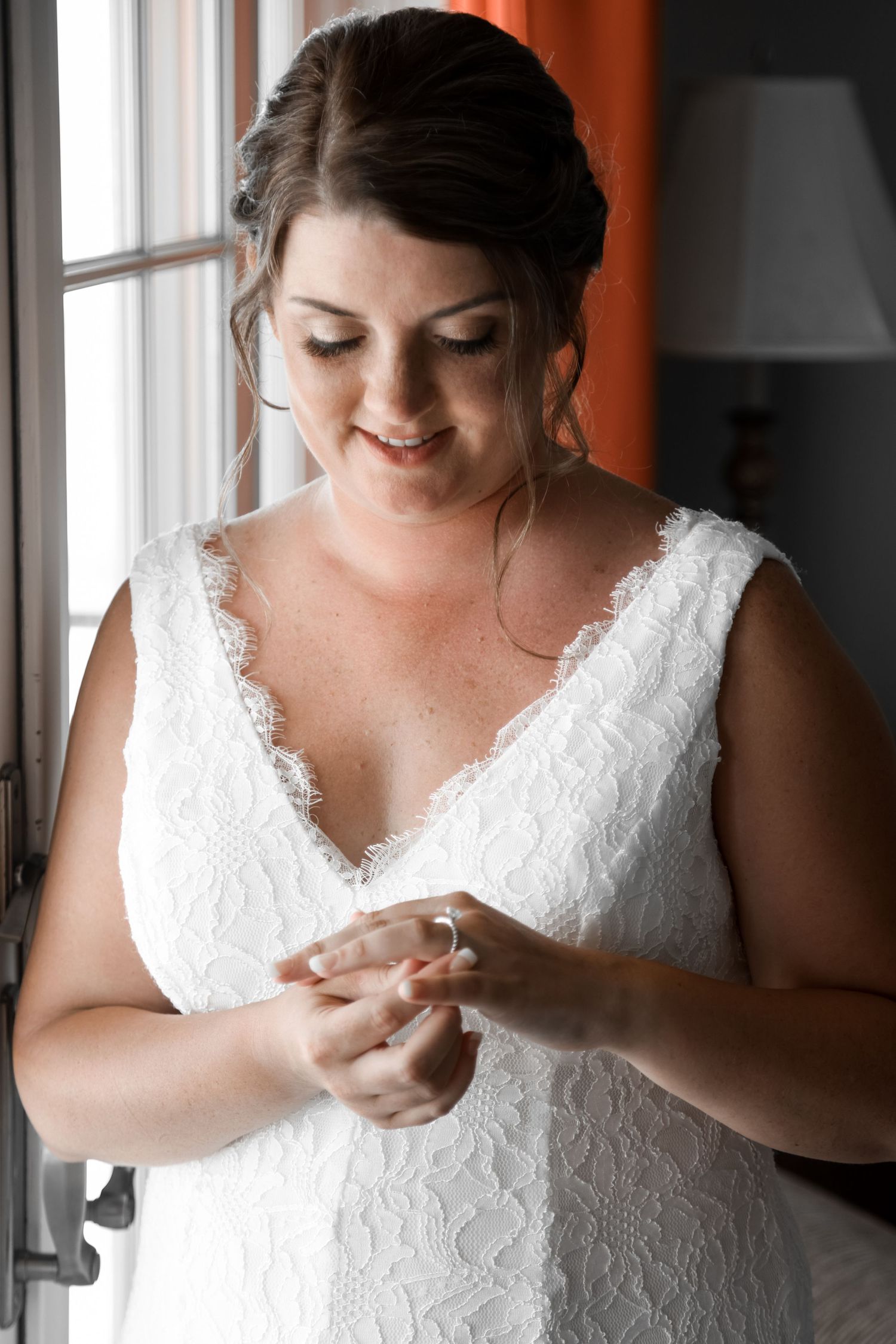 Close-up portrait of someone wearing a white lace wedding dress and looking down.