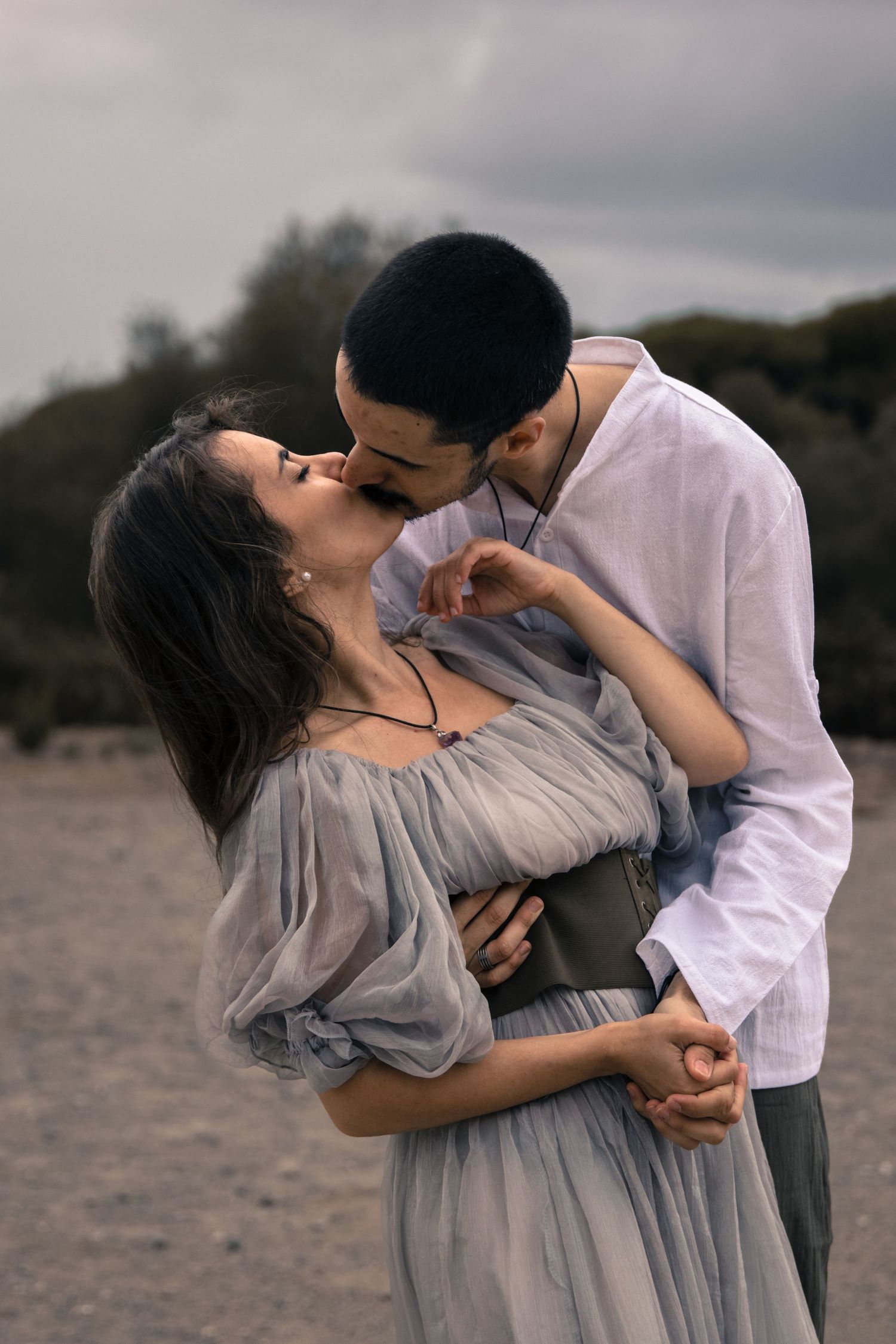 An intimate maternity photoshoot with a flowing gray dress in moody outdoor lighting.