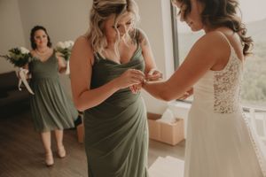 Bridesmaids in sage green dresses helping with final wedding preparation details.