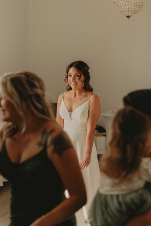 Bride in elegant white dress stands among wedding party members.