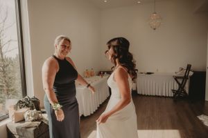 A touching moment during wedding preparations in a bright room with hardwood floors.