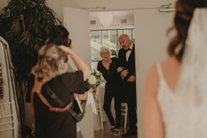Intimate wedding ceremony entrance moment captured in warm, moody lighting.