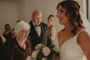 Beautiful indoor wedding moment with floral bouquet and formal attire.