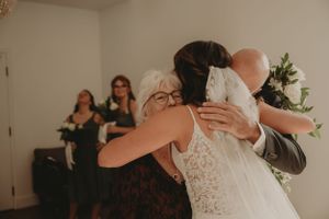 Emotional embrace during wedding celebration with onlookers in background.