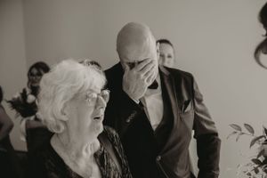 Black and white photo capturing emotional moment at indoor wedding ceremony.