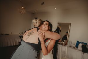 An emotional embrace shared during wedding preparations in a room with chandelier.