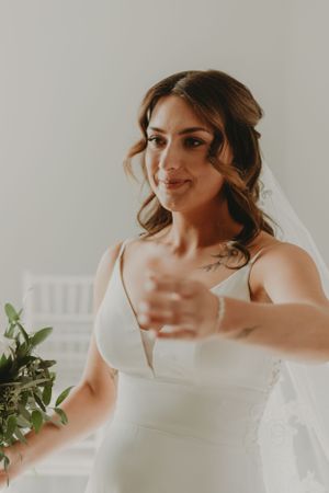 Bride in elegant white wedding dress with V-neck detail and flowing veil.