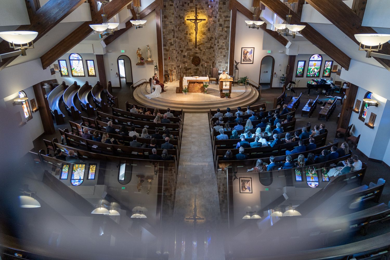 Overhead view of a modern church sanctuary with vaulted ceilings and illuminated altar during a wedding ceremony.