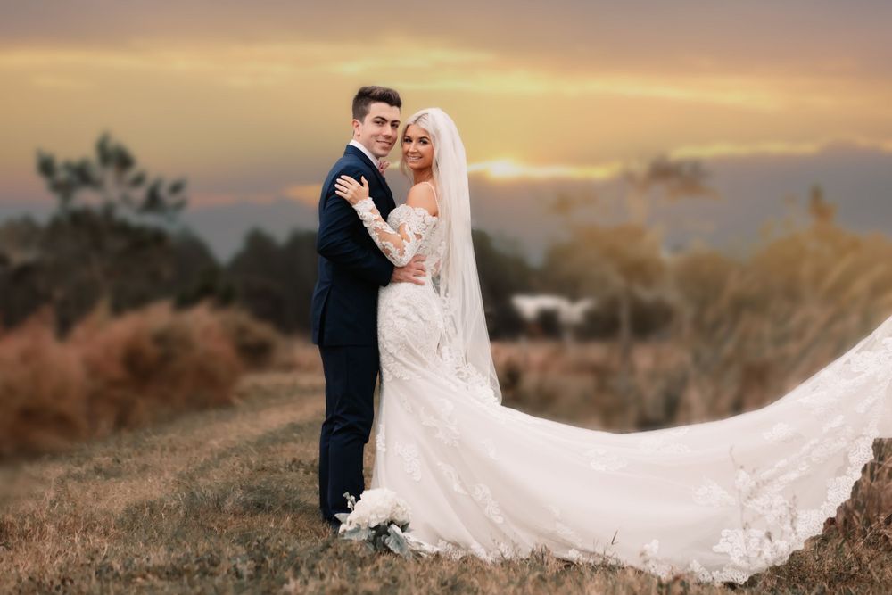 A dreamy sunset wedding portrait with the bride's veil flowing in the wind.