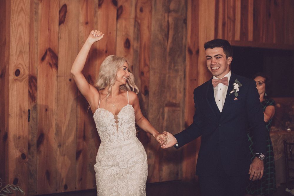 Joyful wedding celebration moment with couple dancing in rustic wooden venue.