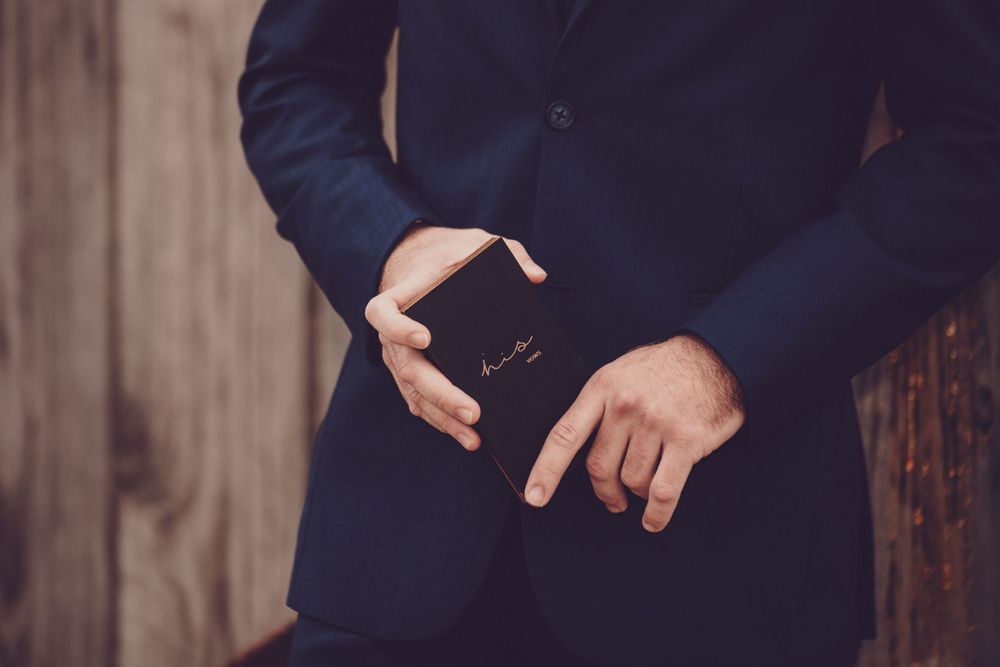 Close up of groom's hands adjusting cufflinks on navy suit jacket.