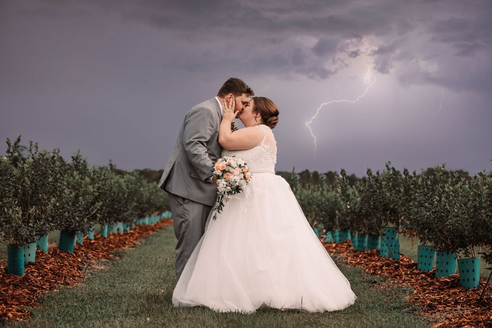 Dramatic wedding photo with lightning strike in background as couple shares intimate moment.