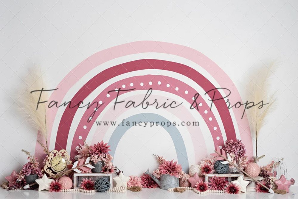 Pink and white rainbow arch backdrop with dried flowers and rustic decor.