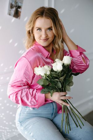 Lifestyle photo with white roses and pink button-down shirt in bright interior.