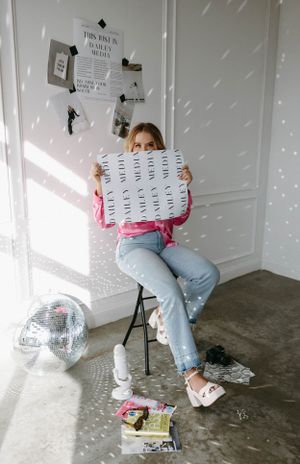 Creative workspace with disco ball and person holding paper against white wall.