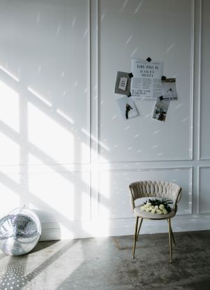 Minimalist room interior with velvet chair and disco ball in natural lighting.