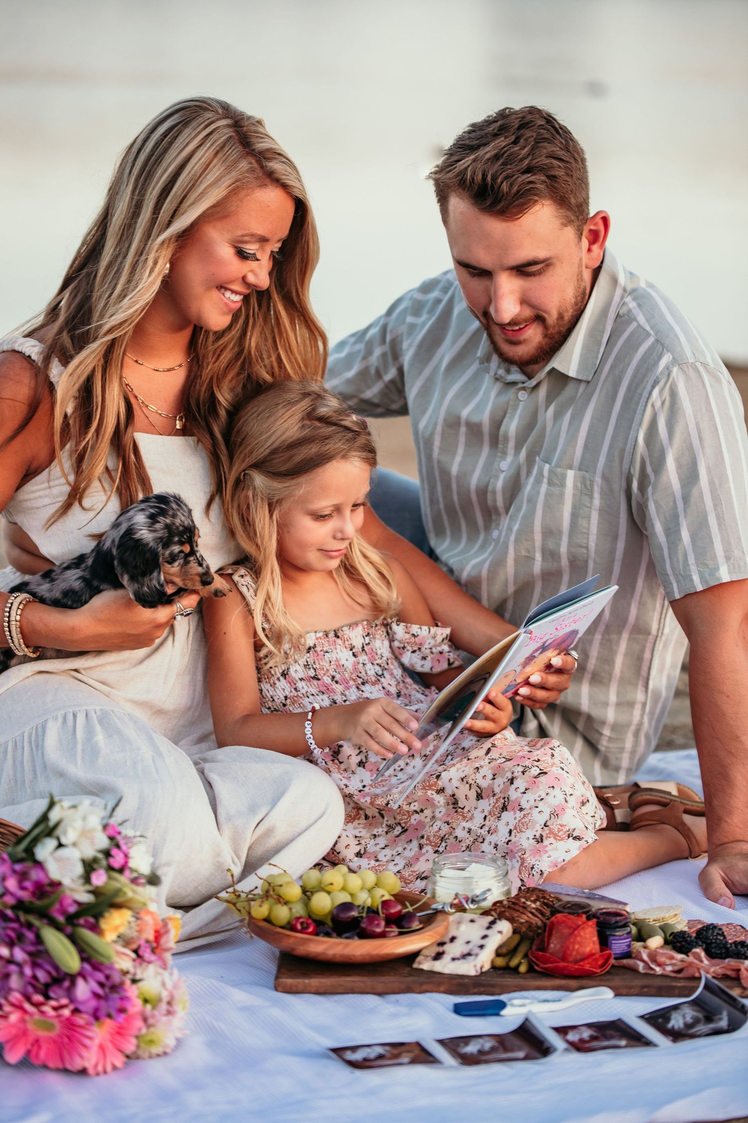 Family picnic scene with flowers, food platter and digital tablet.