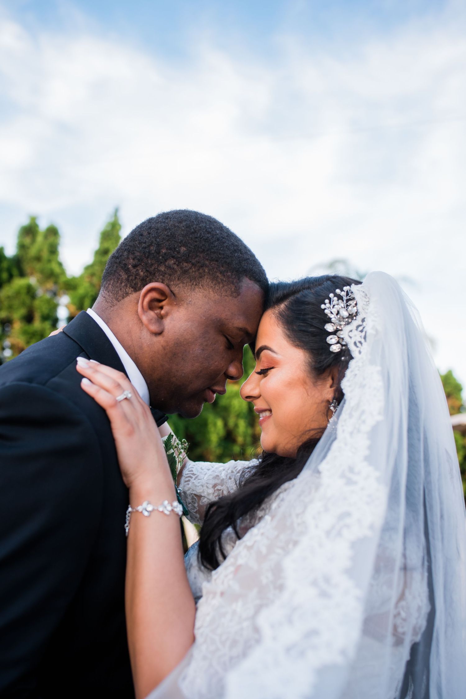A tender moment between newlyweds sharing an intimate embrace while the bride wears a delicate veil and crystal headpiece.