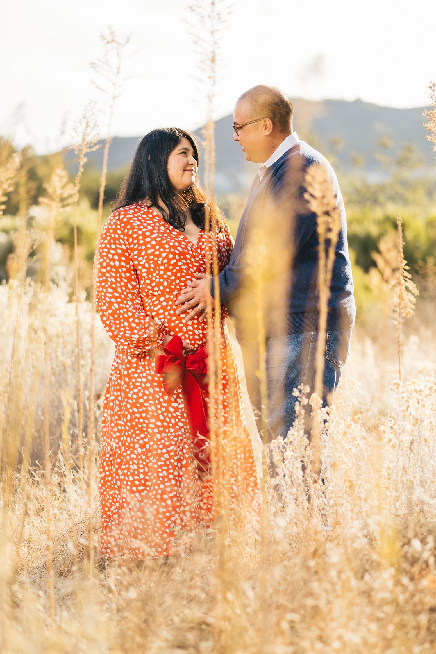 Couple sharing a moment together in a field of dried grass during golden hour.