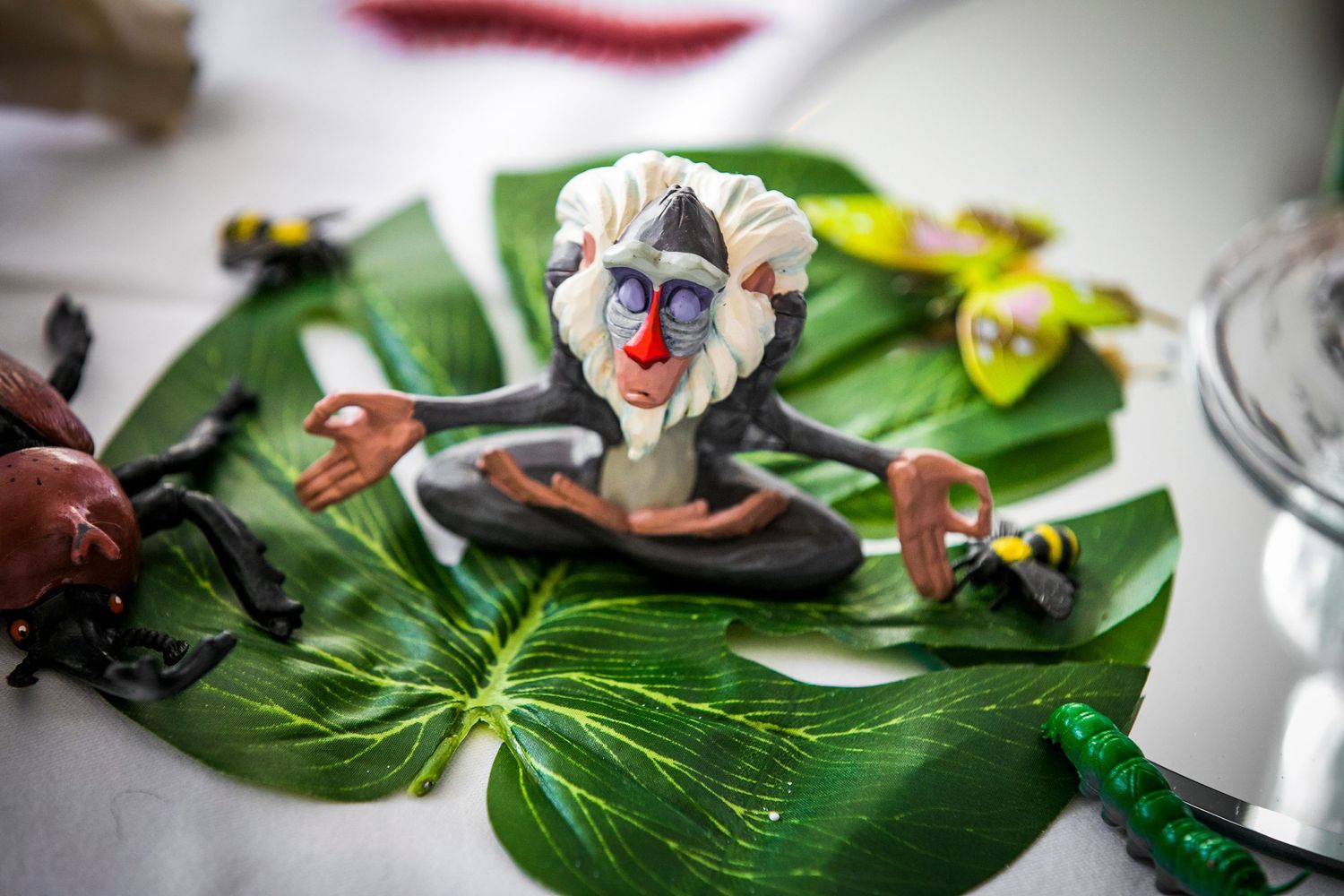 A whimsical clown figurine decoration displayed on a green leaf at a wedding reception.