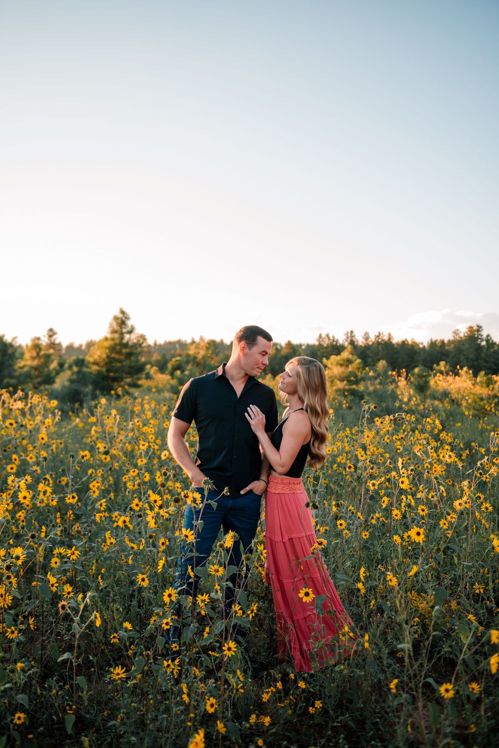 Couple sharing a tender moment in a blooming sunflower field during sunset.