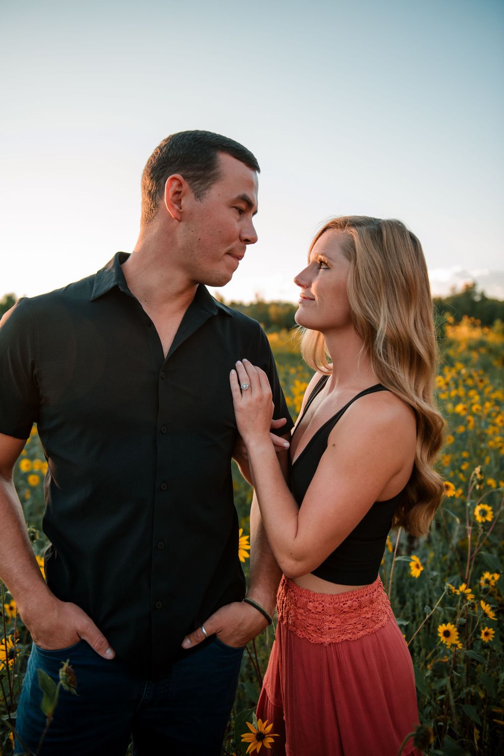 Dancing couple in black and red outfits surrounded by blooming sunflowers.