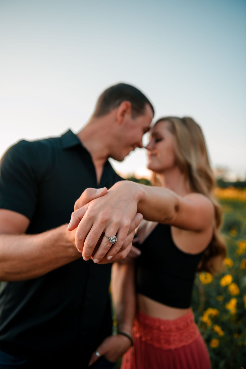 Romantic couple dancing and embracing in a sunflower field at sunset.