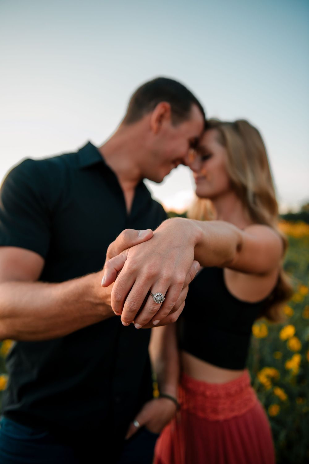 Couple sharing an intimate moment in a golden field of sunflowers.