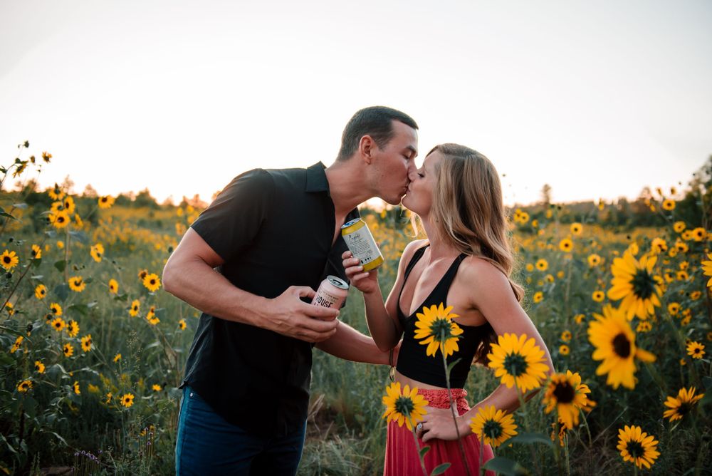 Couple sharing a romantic moment among sunflowers at sunset.