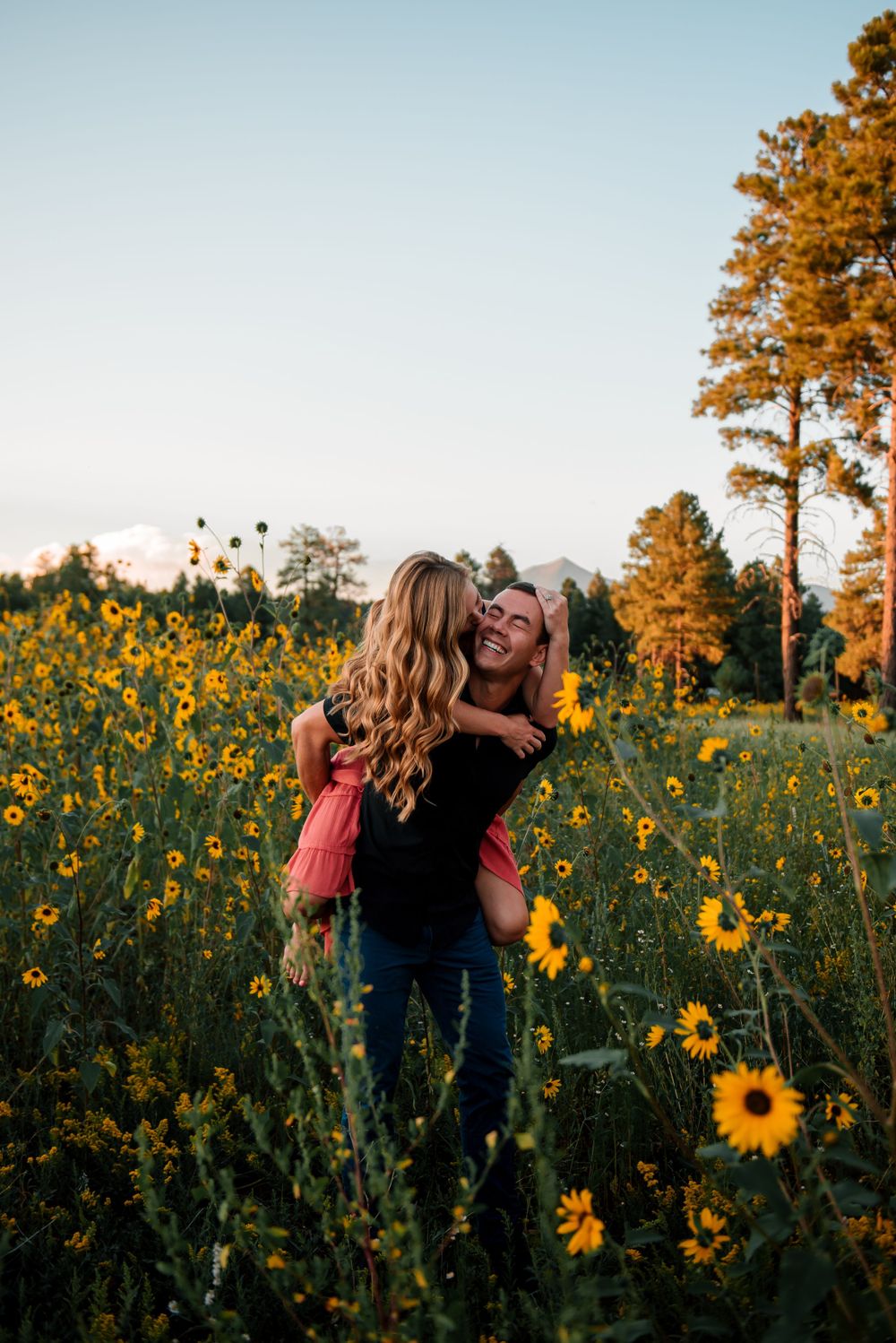Happy couple enjoying a playful moment in a sunflower field.