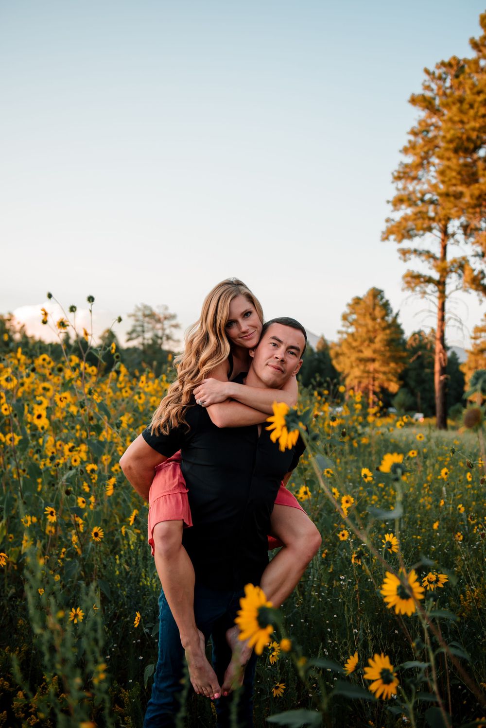 Joyful couple sharing a piggyback ride in a field of sunflowers.