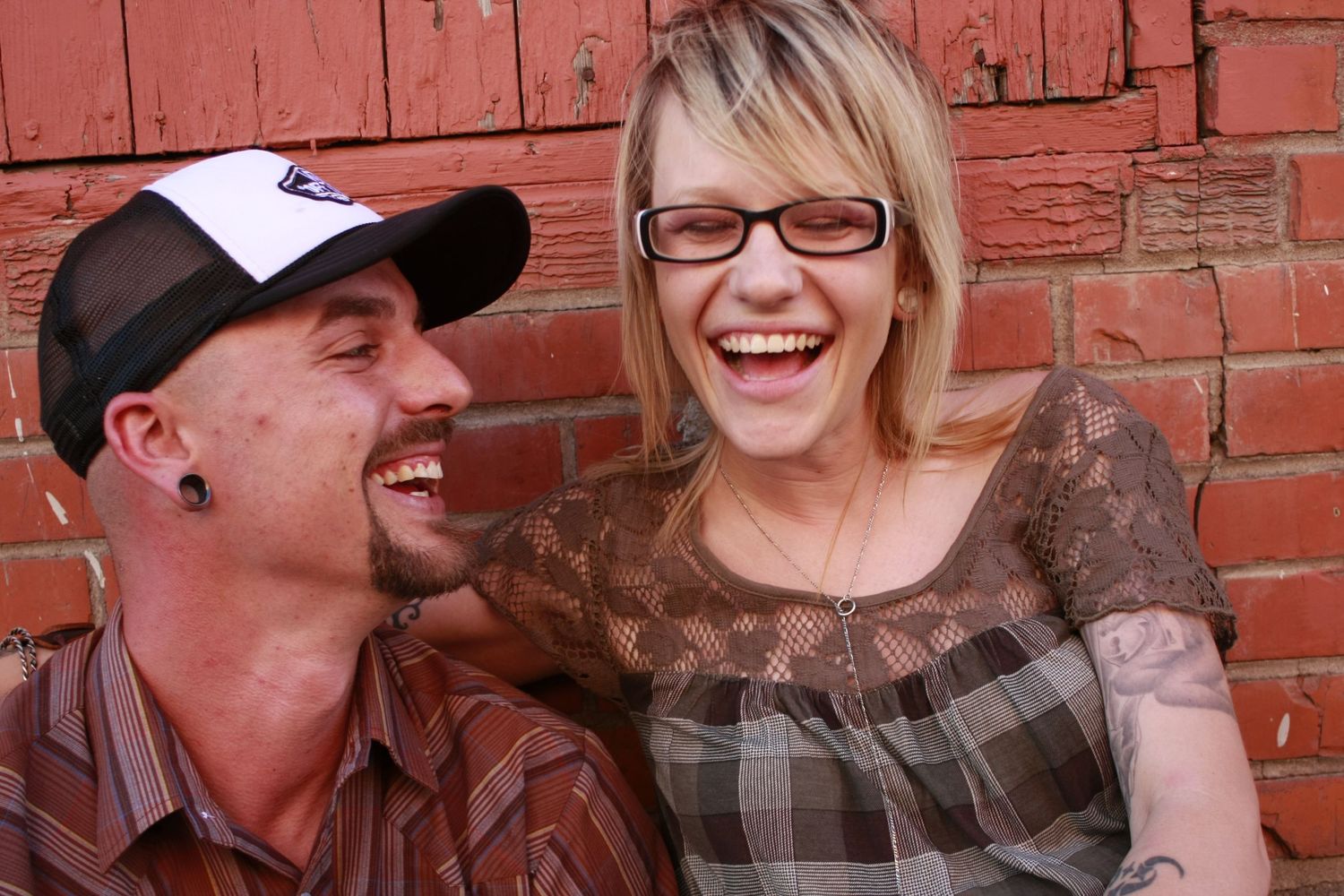 Candid moments captured against a red brick wall showing laughter and joy.