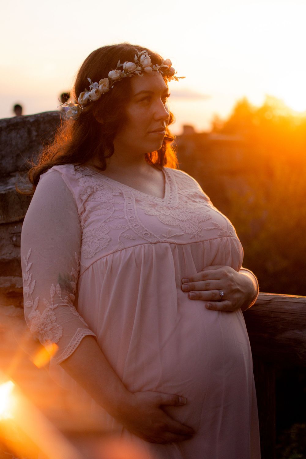 A person in a white vintage-style dress poses against a golden sunset backdrop.