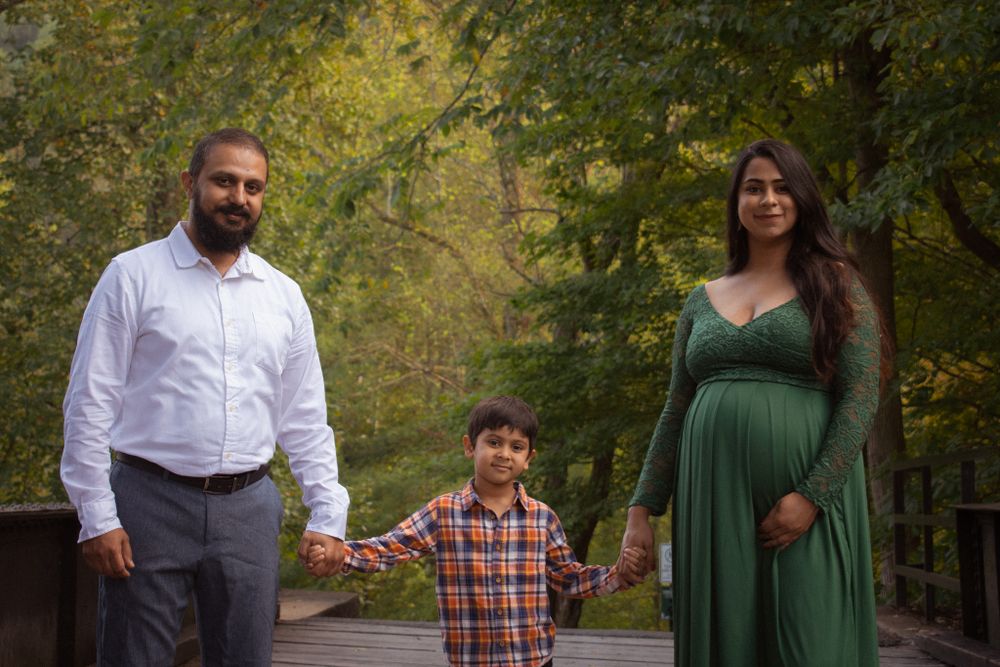 Family photo session in a wooded area with casual attire and natural lighting.