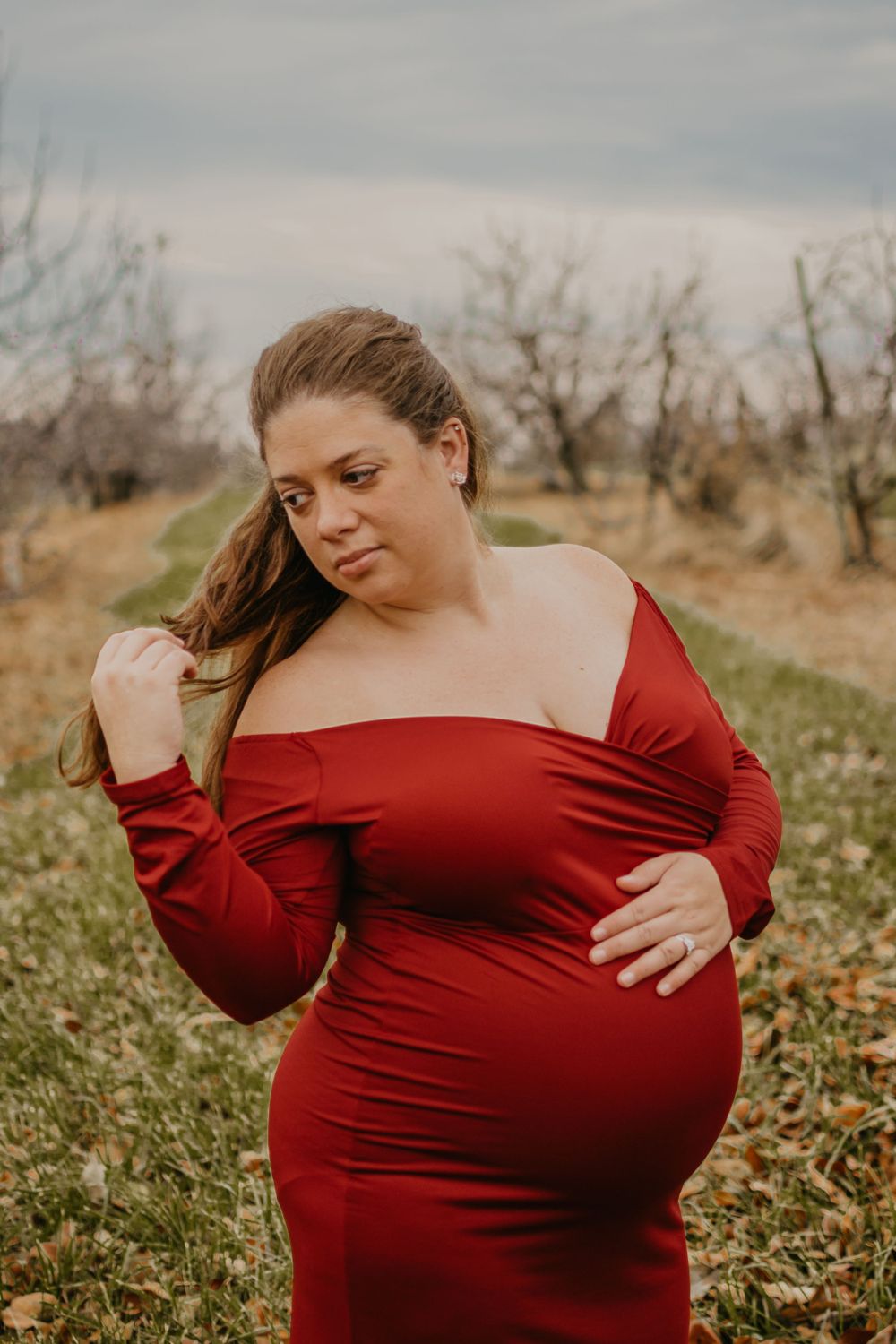 Candid maternity portraits showing woman in red dress embracing pregnancy.