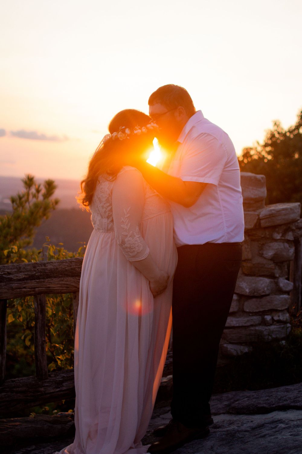 A romantic sunset photoshoot featuring a couple embracing on rocky terrain.