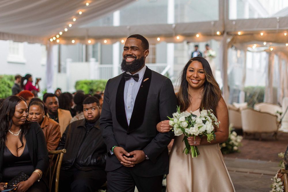 Joyful wedding ceremony processional in a tented venue with elegant decor.
