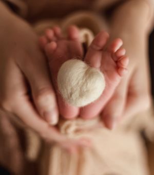 Artistic detail shots of tiny newborn feet and hands against soft fabric.