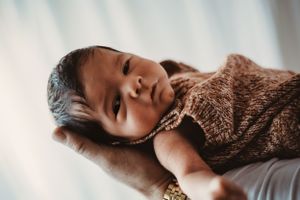 Peaceful sleeping newborn wrapped in soft brown textiles.